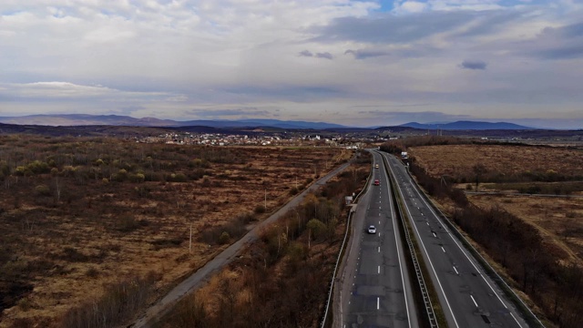 道路穿过低洼的山坡，黑暗而沉重的色调的道路是贫瘠的，长满了天空的乌云。视频素材