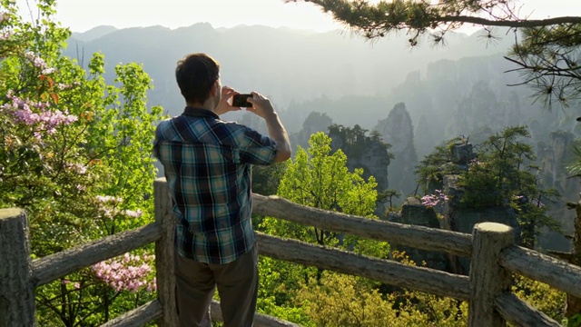 一名男子用智能手机拍摄日落时分的山景。UHD 4 k视频素材