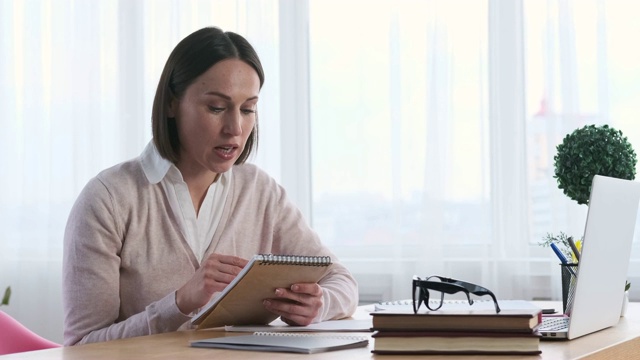 女商人一边用笔记本电脑开会，一边用记事本视频素材