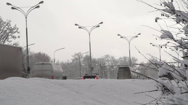 汽车在雪堆后面的冬季城市道路上行驶。第1部分。视频下载