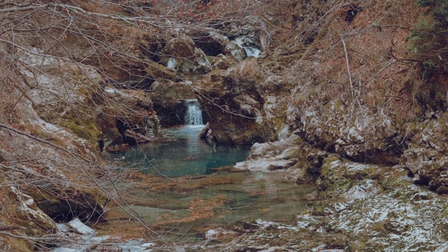 第一场雪落在一条美丽、晶莹剔透的小河上，小溪穿过满是岩石的峡谷。视频素材