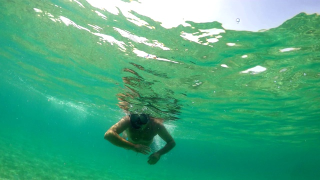 戴着潜水面罩的人在海面上游泳寻宝，gopro半水下视野视频素材