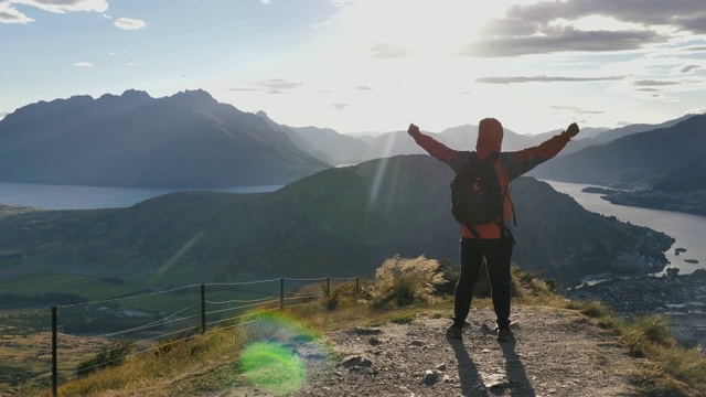 在阳光灿烂的日子里，登山的人成功地站在山顶上视频素材