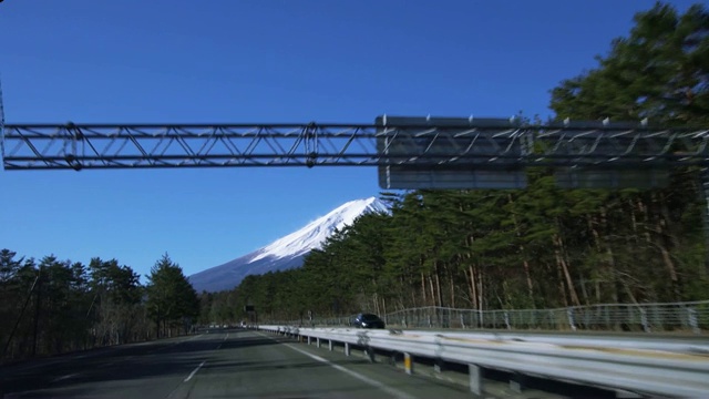 车上的摄像头拍摄的画面是穿过大门，沿着富士五湖步道跑，看着前面的富士山，视频素材