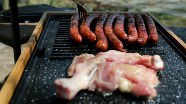 一个男人在为野餐的朋友准备烤鸡肉和香肠视频素材