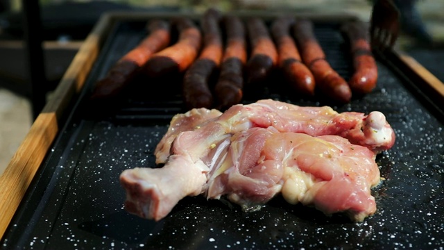 一个男人在为野餐的朋友准备烤鸡肉和香肠视频素材