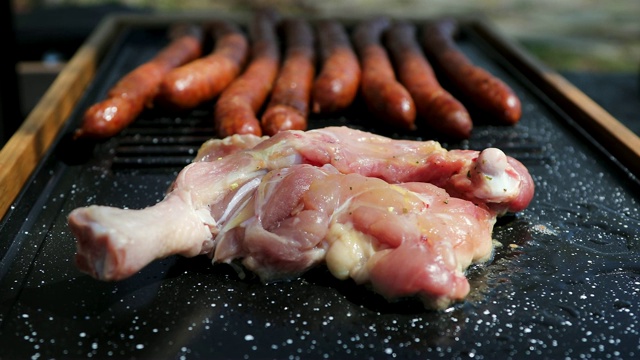 一个男人在为野餐的朋友准备烤鸡肉和香肠视频素材