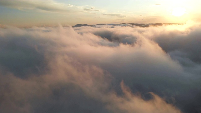 在黄昏或黎明飞过云层。飞行在粉红色的云在太阳鸟瞰图。视频素材