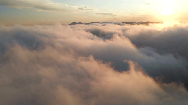 在黄昏或黎明飞过云层。飞行在粉红色的云在太阳鸟瞰图。视频素材