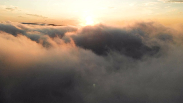 在黄昏或黎明飞过云层。飞行在粉红色的云在太阳鸟瞰图。视频素材