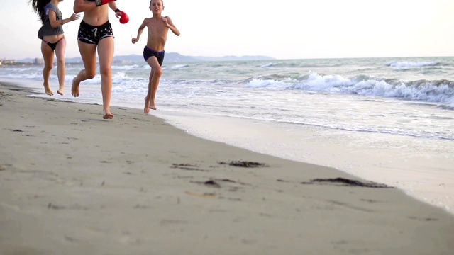 Three children jogging on beach at sunrise, cinematic doof三个孩子在日出时在海滩上慢跑，cinematic doof视频素材