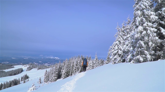 一位游客在山中的雪中行走。视频素材