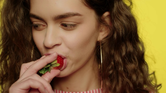 性感女孩在工作室吃草莓水果。年轻女子吃草莓视频素材