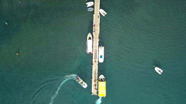 从空中俯瞰瓜德罗普岛加勒比海海湾的一艘浮码头上的船只和帆船。加勒比海蓝色海水的美妙景色。视频素材