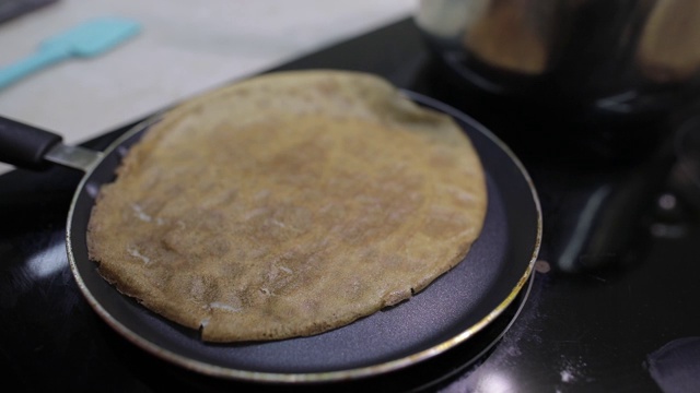 自制煎饼的制作过程。女人在煎锅里翻薄饼视频素材