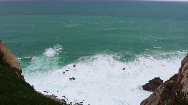 海浪拍打着岩石。有蓝色海浪，白色泡沫和岩石的海景。从悬崖上看到的地平线。阴暗的天气视频素材