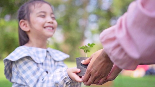 可爱的小亚洲女孩把小植物送给妈妈，拯救地球的理念。视频素材