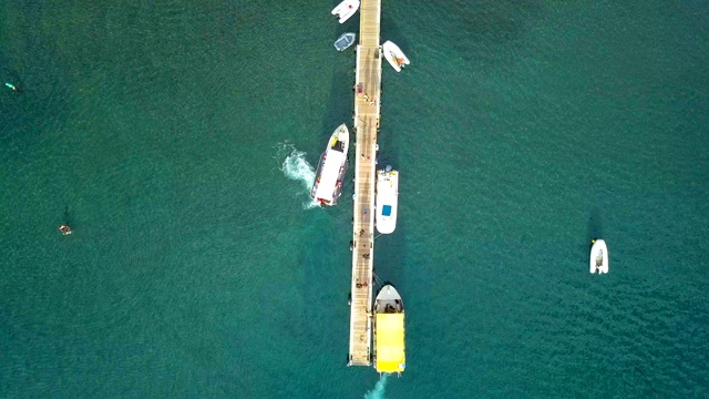 从空中俯瞰瓜德罗普岛加勒比海海湾的一艘浮码头上的船只和帆船。加勒比海蓝色海水的美妙景色。视频素材