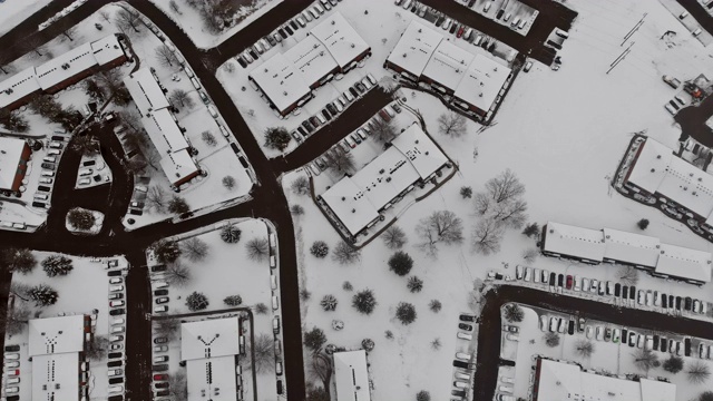 从高处俯瞰城市街道上的房屋被雪覆盖的建筑物，城市阴沉沉的灰色天空下的景象。视频素材