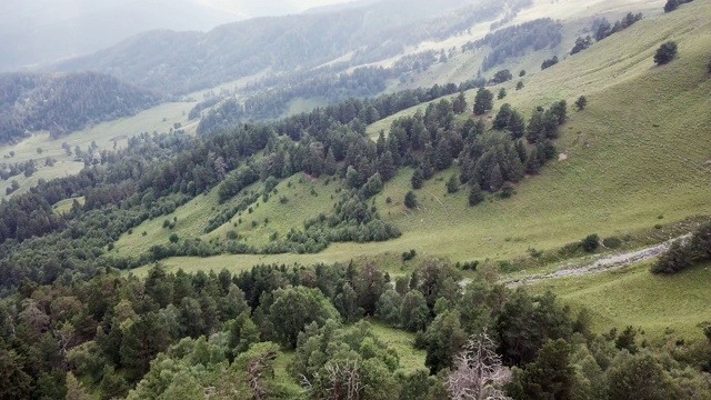 鸟瞰图。飞过绿草嶙峋的山丘。在美丽的云中飞过高山视频素材