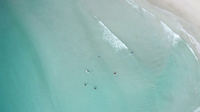 空中上升/右旋:冲浪者在浅蓝色的海水海岸-埃斯佩兰斯，澳大利亚视频素材