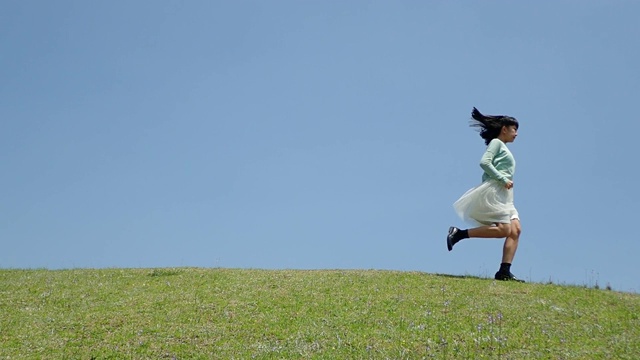 一个日本女孩在蓝天上奔跑视频素材