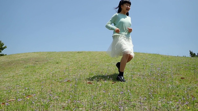 一个日本女孩在蓝天下跑下山坡视频下载