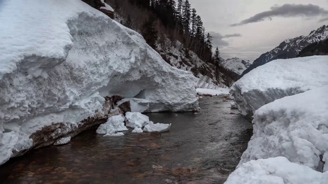 雪片从山上雪崩在河的背景山峰视频下载