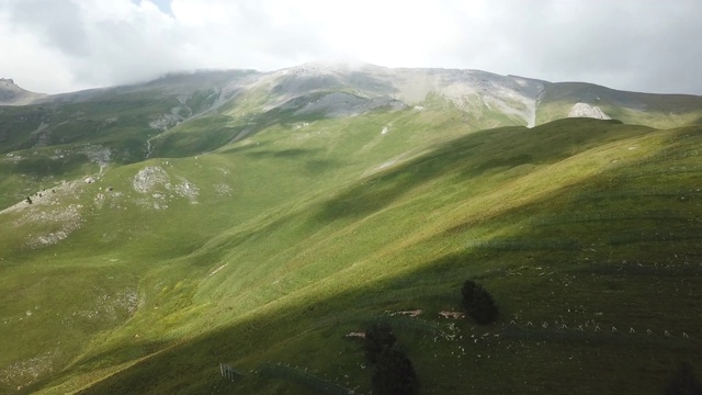 鸟瞰图。飞过绿草嶙峋的山丘。在美丽的云中飞过高山视频素材