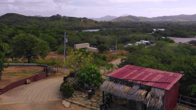 空中盘旋/下降:树覆盖的海岸上的建筑物，小山距离-尼加拉瓜的埃尔吉甘特视频素材