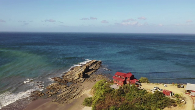 空中向前:在充满活力的蓝色海洋的岩石海岸上的大型红房子-尼加拉瓜的埃尔吉甘特视频素材