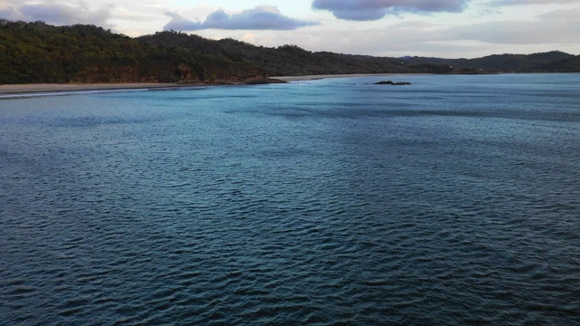 空中向前/左图:深蓝色的海洋，海岸上有森林覆盖的山丘-尼加拉瓜埃尔吉甘特视频素材