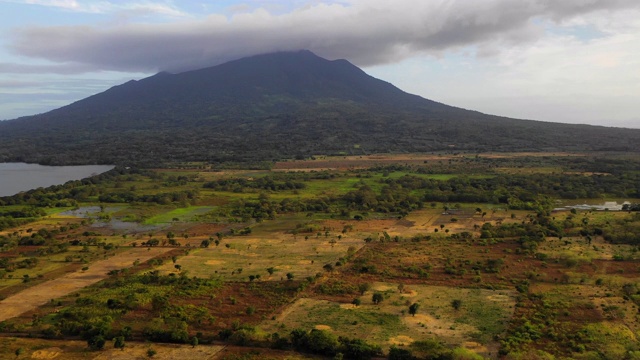 空中Pan Up:绿色山谷周围的黑暗火山，烟雾之上- Ometepe，尼加拉瓜视频素材