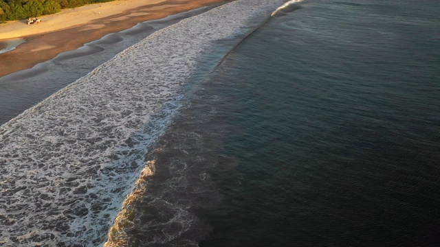 空中向前/向下平移:傍晚阳光下海岸上的黑暗海浪- El Gigante，尼加拉瓜视频素材