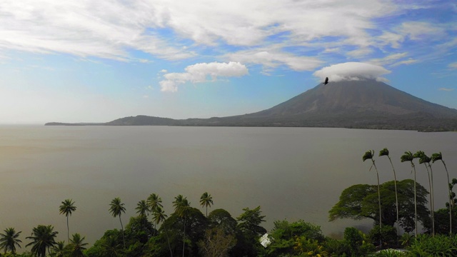 右图:尼加拉瓜，奥米特佩，海洋边缘的树木和火山，烟在对面视频素材