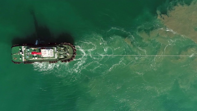 高空鸟瞰图拖船在海上拖着集装箱船到集装箱仓库进行物流，进出口或运输。视频素材