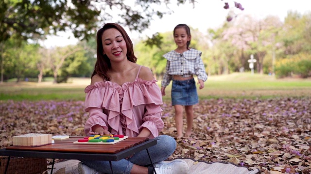 可爱的亚洲女孩和妈妈玩七彩拼图在周末的公园。缓慢的运动。视频素材