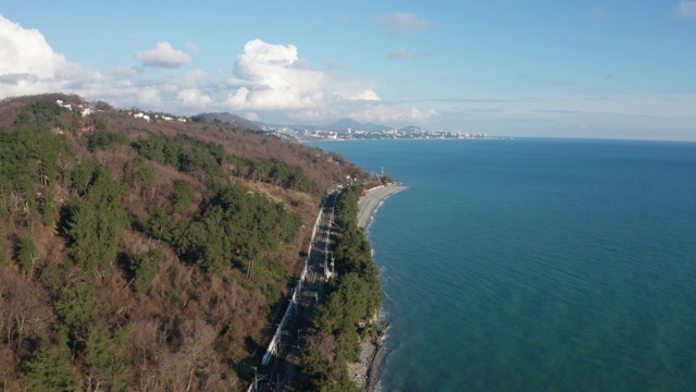 从空中鸟瞰蓝色海洋的视频。海边的度假小镇。沿着海岸飞行。清澈的蓝绿色海洋。云在山上的天空。俄罗斯索契度假胜地。视频素材