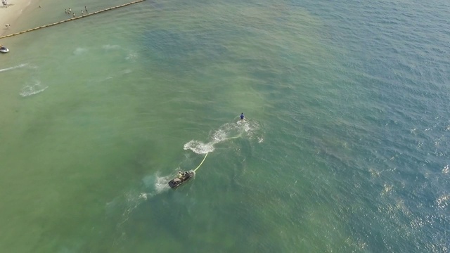 年轻人骑在飞板与水喷射在蓝色的海水。在公海上驾驶滑板。暑假水上运动。游泳运动。夏天的活动视频素材