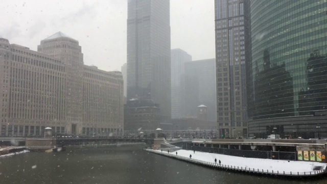 芝加哥河上大雪纷飞，通勤者在河边人行道上冒着严寒。视频下载