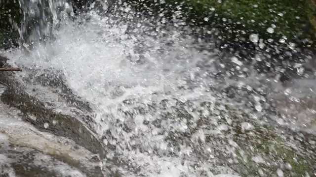 在慢镜头潮湿的森林里，山洪倾泻在岩石上视频素材