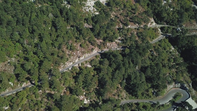 鸟瞰图山形蜿蜒的道路与卡车和汽车。股票。道路交通蜿蜒在高山狭窄的角落，汽车变成绿色的森林视频素材