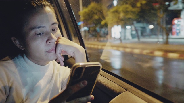 一个年轻的亚洲女人在车里用智能手机。视频素材