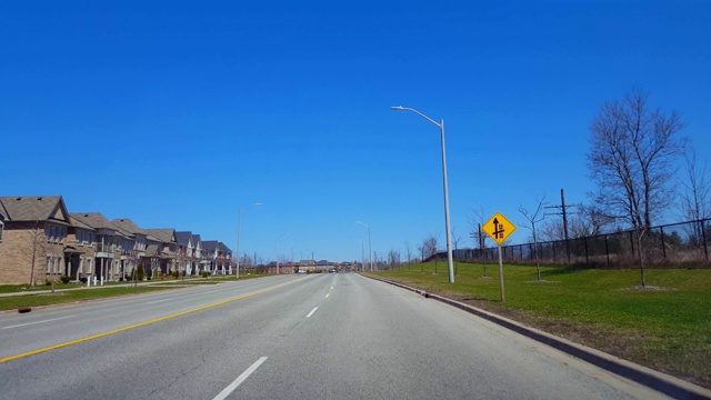 在春日驾驶住宅道路。司机视角沿着美丽的阳光郊区街道。视频素材