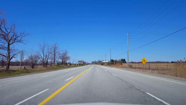 在春日沿着农田行驶的乡村道路。司机视角POV美丽的阳光乡村农场。视频素材