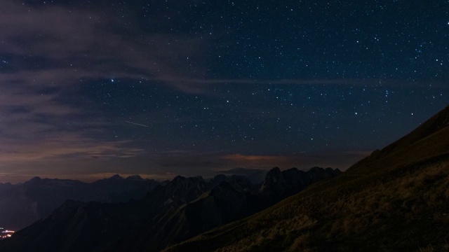 随着时间的推移，美丽的夜晚星星和山景观覆盖在云。视频下载