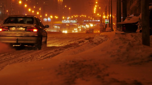 城市遭遇暴风雪天气。城市里的交通在下雪的夜晚。视频素材