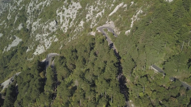 弯弯曲曲的山道边有悬崖峭壁，鸟瞰高山。股票。鸟瞰图景观，蜿蜒的山路在夏季阳光明媚的日子背景视频素材