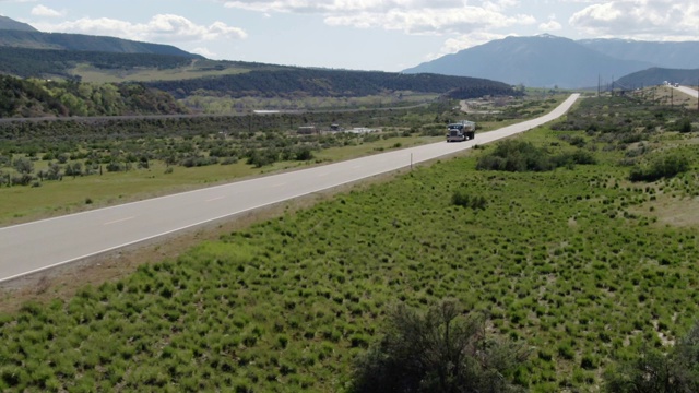 无人机拍摄到一辆半卡车在科罗拉多落基山脉的70号州际公路上行驶，这是一个阳光明媚，部分阴天视频素材