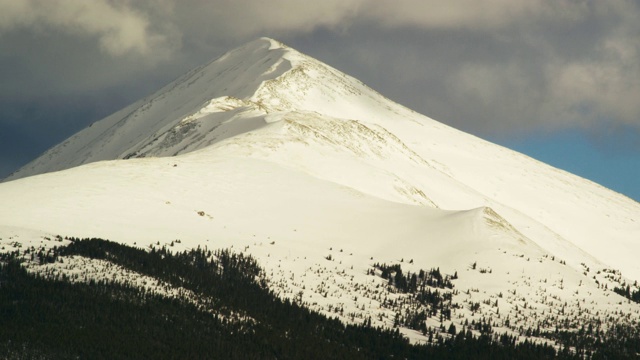 一个被照亮的雪峰在洛基山脉附近的弗里斯科，科罗拉多州在暴风雪云下的冬天视频素材